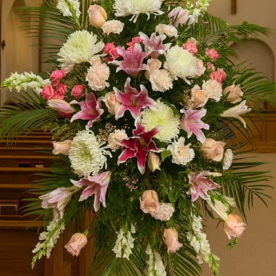 Large pink and white funeral spray with lilies and roses in a church