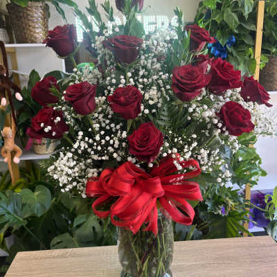Red roses and baby's breath in a glass vase with a red ribbon