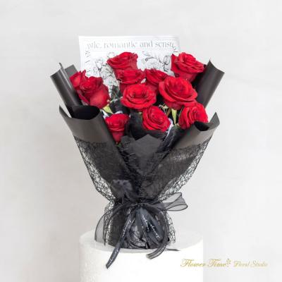 Bouquet of red roses wrapped in black paper with a ribbon