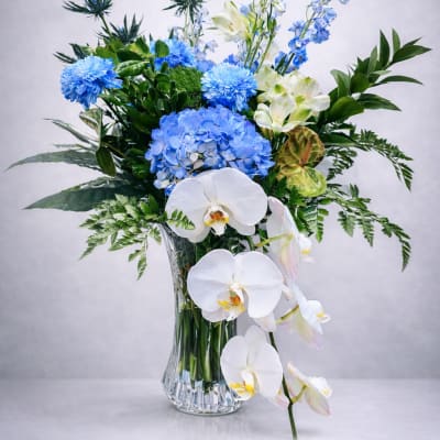 Blue and white floral arrangement in a clear glass vase