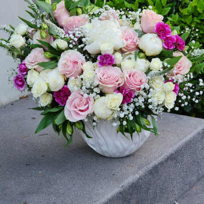Pink and white rose arrangement in a white ceramic vase