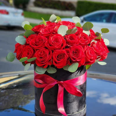 Red roses in a black hatbox with a pink ribbon