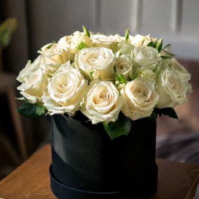 Cream roses arranged in a black hatbox