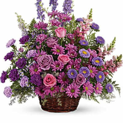 Purple and pink mixed flower basket arrangement in a wicker basket