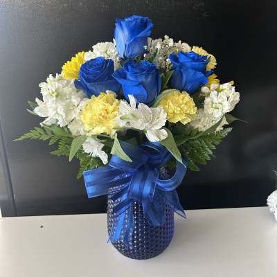Blue roses with white and yellow flowers in a blue vase