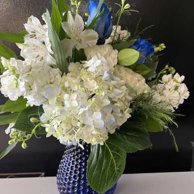 White and blue floral arrangement in a cobalt glass vase
