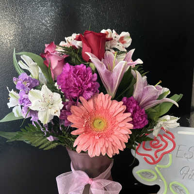 Mixed bouquet with pink gerbera, roses, lilies, and purple flowers in a vase