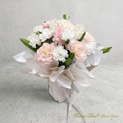 Bouquet of pale pink and white carnations wrapped in white paper