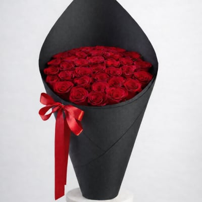 Red roses arranged in a black cone wrap with a red ribbon