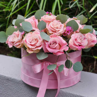 Pink roses arranged in a round pink box with a ribbon