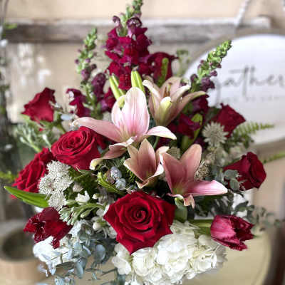 Bouquet of red roses, pink lilies, and white hydrangeas in a glass vase