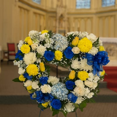 Heart-shaped floral wreath with blue, yellow, and white flowers