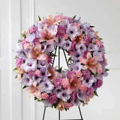 Round wreath of pink and lavender flowers on a black stand