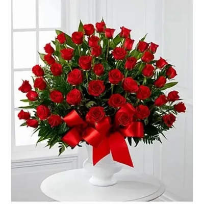 Large bouquet of red roses in a white vase with a red ribbon