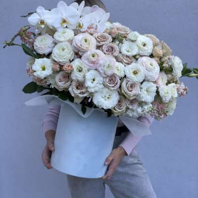 Large bouquet of white orchids and pale roses in a white box