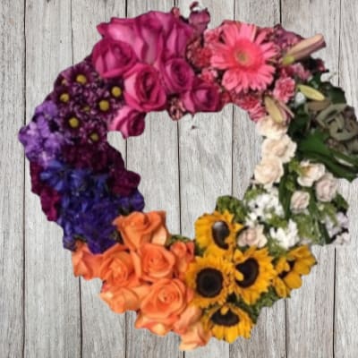 Heart-shaped floral wreath with multicolored flowers on a wood background