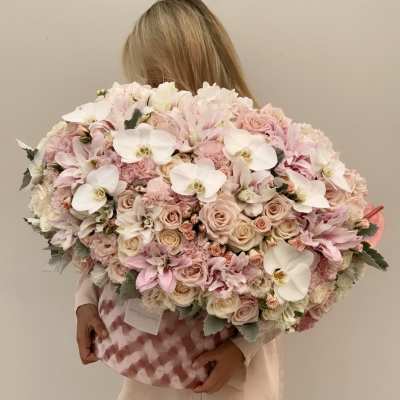 Large pastel bouquet of roses, orchids, and white blooms in a pink patterned box