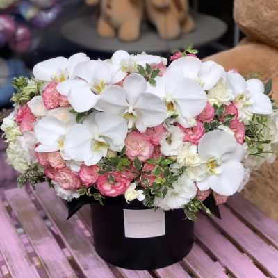 Pink and white floral arrangement in a black hat box