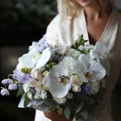 Woman holding a bouquet of white orchids and pale flowers