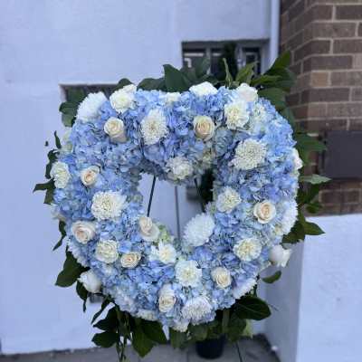 Heart-shaped blue and white floral wreath on a stand