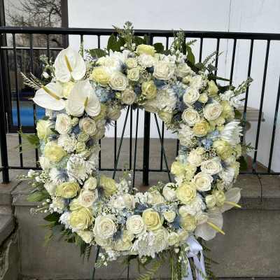 Large white floral wreath on an easel with roses and calla lilies