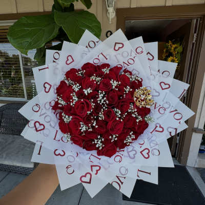 Large bouquet of red roses wrapped in white paper with heart and love text