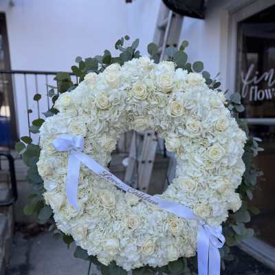 White floral wreath on an easel with a ribbon