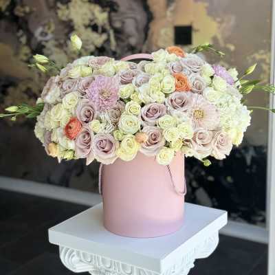 Pastel roses and dahlias arranged in a pink hat box