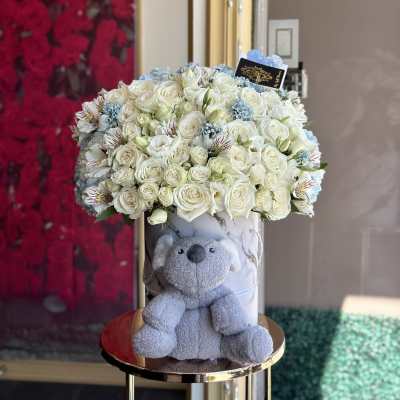 White rose bouquet in a marble box with a gray teddy bear