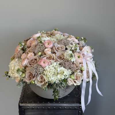 Large pastel bouquet of roses, ranunculus, and hydrangeas with a ribbon