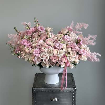 Large pink and white floral arrangement in a white pedestal vase