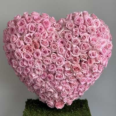 Heart-shaped arrangement of pink roses on a moss-covered base