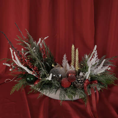 Holiday centerpiece with frosted evergreens, red berries, and ornaments in a white bowl