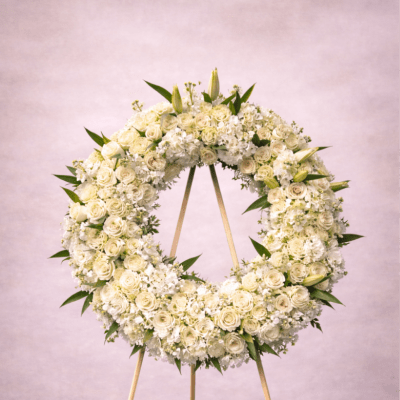 Large white floral wreath on a wooden easel against a soft neutral background
