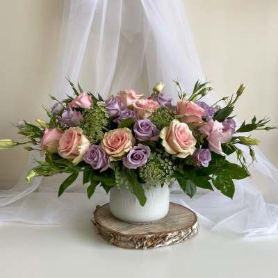 Pink and lavender roses arranged in a white vase