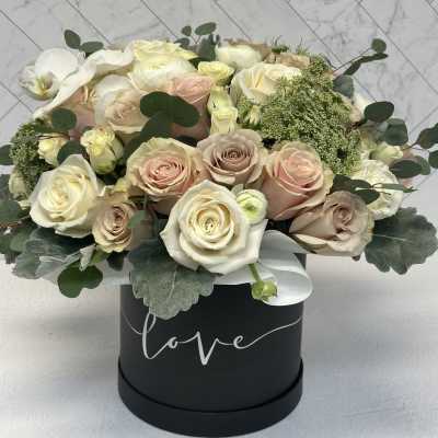 Bouquet of pale roses and white orchids in a black hat box