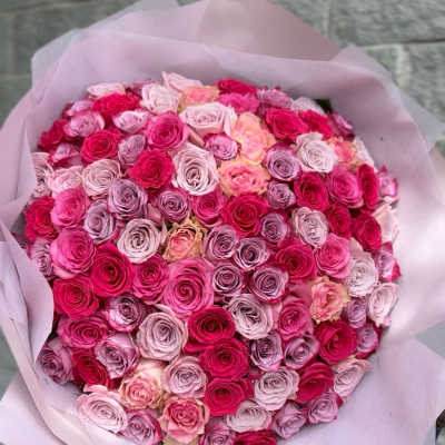 Large bouquet of pink and lavender roses wrapped in pale pink paper