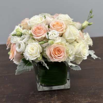 Bouquet of peach and white roses in a square glass vase