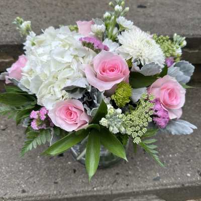 Pink roses and white flowers arranged in a glass vase