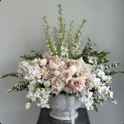 Large pale pink and white floral arrangement in a gray vase