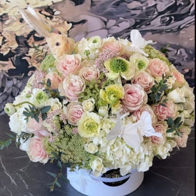 Round bouquet of pale pink and white flowers in a white hat box