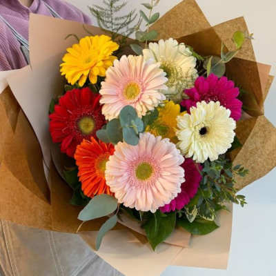 Bouquet of multicolored gerbera daisies wrapped in brown paper