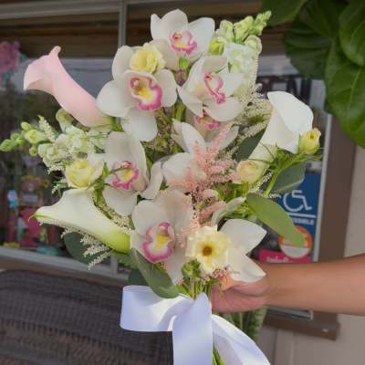 Bouquet of white orchids, calla lilies, and pale roses with a white ribbon