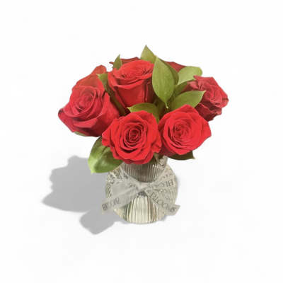 Red roses in a clear glass vase with a ribbon bow