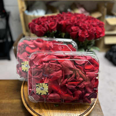 Red rose bouquet in clear plastic boxes on a wooden tray