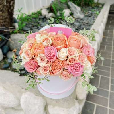 Round bouquet of pink, peach, and cream roses in a white hat box