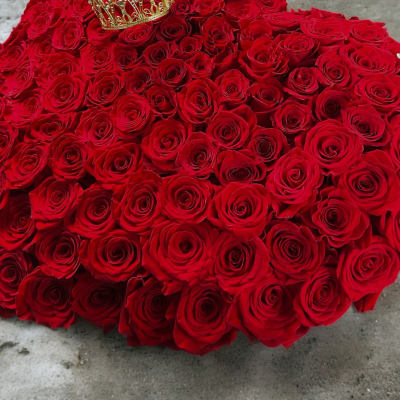 Heart-shaped arrangement of red roses with a gold crown on top