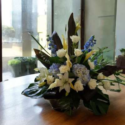 White and blue floral arrangement in a low container on a table