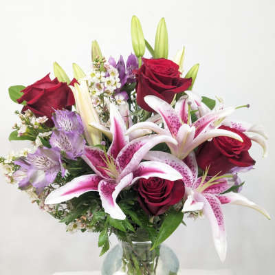 Bouquet of red roses and pink lilies in a clear glass vase