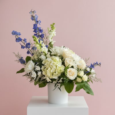 White roses and hydrangea in a white vase with blue flowers